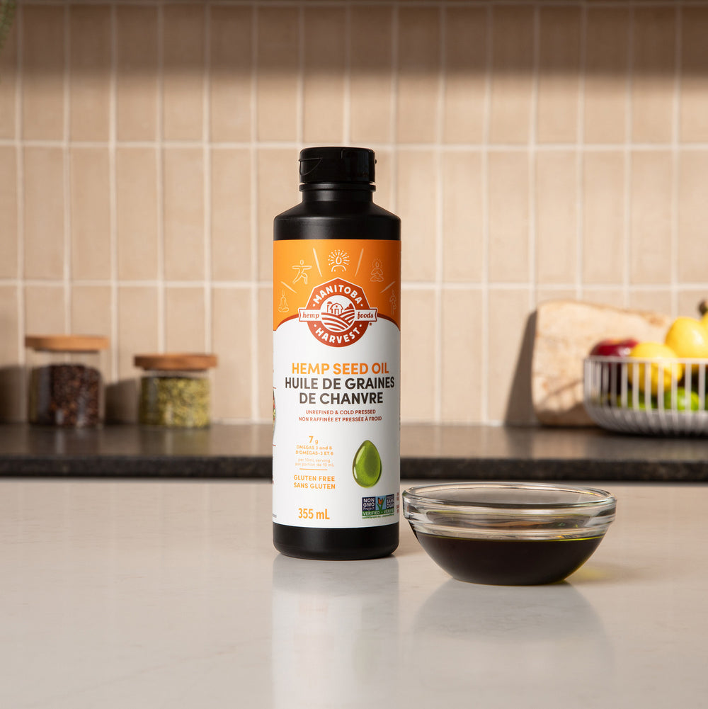 Bottle of hemp seed oil on a kitchen counter with a bowl of oil next to it.
